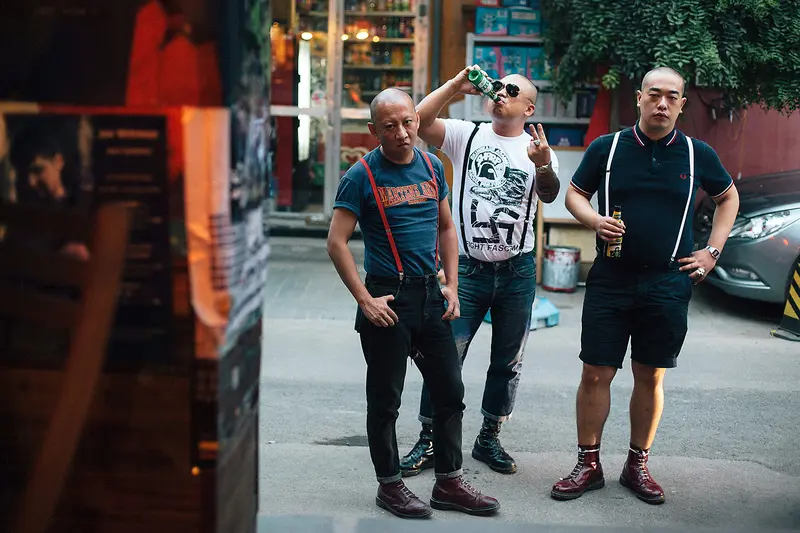 Three Chinese skinheads in braces and Fred Perry shirts wearing oxblood and black Dr. Martens boots