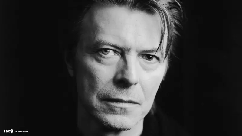 Black and white close-up portrait of a man with swept-back hair staring intently into the camera
