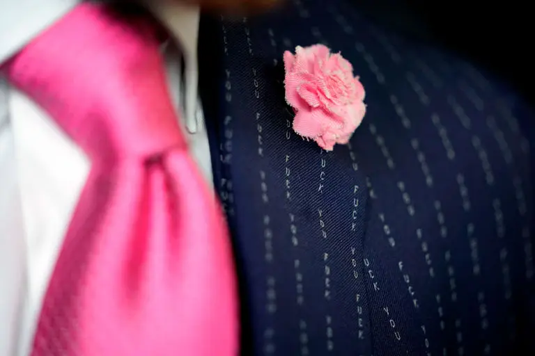 Close-up of McGregor's navy suit: the pinstripes spell 'Fuck You' repeatedly, beside a pink tie and lapel flower