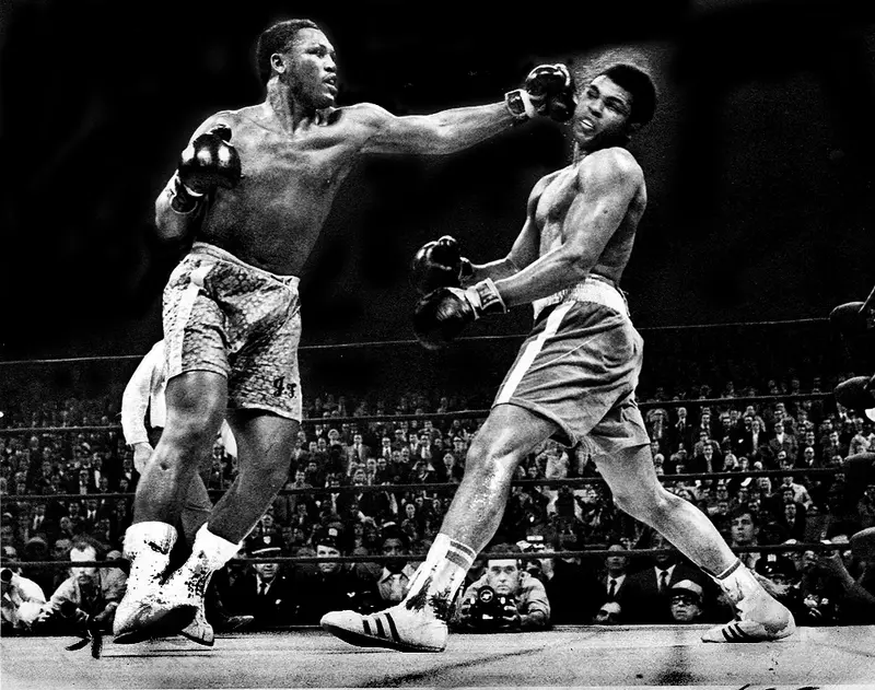 Black-and-white photo of Joe Frazier landing a left jab on Muhammad Ali in the ring