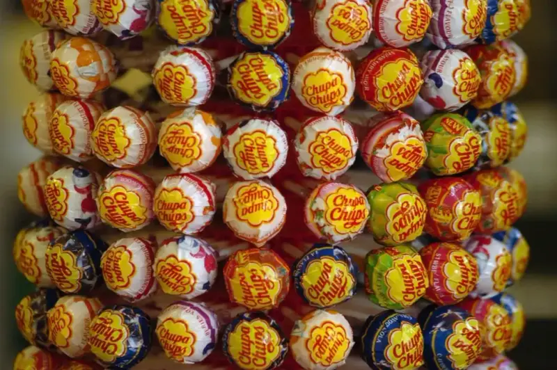 Rows of Chupa Chups lollipops in different flavours, each wrapper topped with the daisy logo