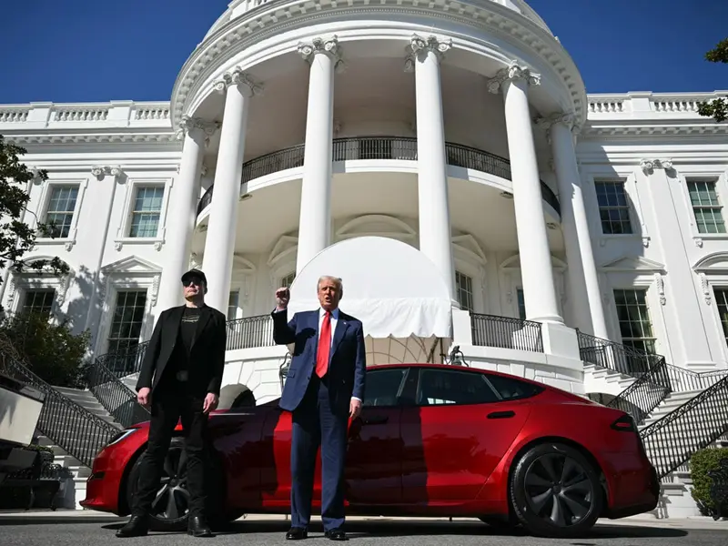 Elon Musk and Donald Trump standing beside a red Tesla Model S outside the White House